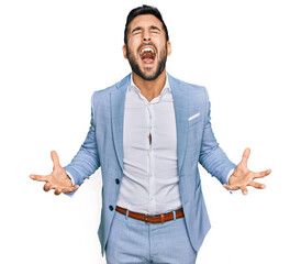 Young hispanic man wearing business jacket crazy and mad shouting and yelling with aggressive expression and arms raised. frustration concept. - obrazy, fototapety, plakaty