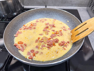 Egg omelette with sausages turn over with a spatula cooking in a Frying Pan.