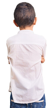 Cute blond kid wearing elegant shirt standing backwards looking away with crossed arms