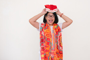 Isolated portrait of Asian woman standing over white background trying to fix Santa's red hat for...