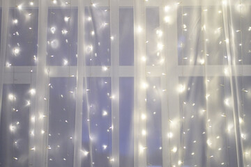 Led light wall garlands, string lights on white tulle fabric backdrop, background with copy space....