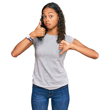 Young african american girl wearing casual clothes doing thumbs up and down, disagreement and agreement expression. crazy conflict