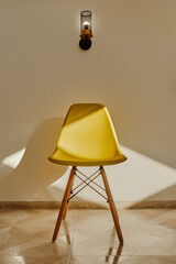 Yellow chair and lamp in the interior with sunlight and shadow from window. Suitable for interior design concepts. Interior of living room with yellow chair near the wall. Selective focus