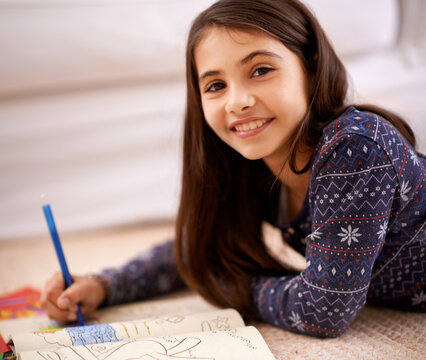 Girl, coloring book and portrait on floor for drawing in home with learning, development and lying in lounge. Kid, art and smile for sketch, creativity and relax on carpet at family house in Madrid