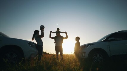 happy family play ball next to car silhouette a camping vacation. Road trip fun. happy family adventures with car travel and camping silhouette. car travel and silhouette camping expedition sunset - obrazy, fototapety, plakaty
