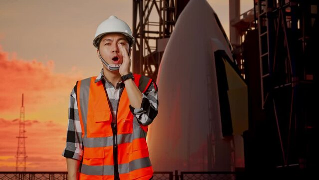 Asian Male Engineer With Safety Helmet Yelling With Hand Over Mouth While Standing With Space Shuttle, Sunset Time