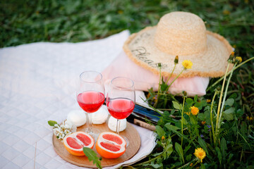 A picnic in the spring garden on a blanket. Large glasses with orange juice. Grapefruit. Green grass. Relaxation vibe