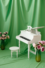Children's small piano on a green background. Musical development. Spring flowers