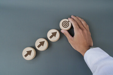 Businessman's hands place arrow and target symbols on wooden blocks. The concept of setting goals...