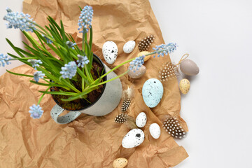 Easter eggs and light blue muscari flowers in cup on a white table. Easter still life. Top view - 767840449