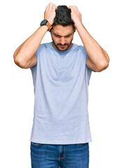 Fototapeta premium Young hispanic man wearing casual clothes suffering from headache desperate and stressed because pain and migraine. hands on head.