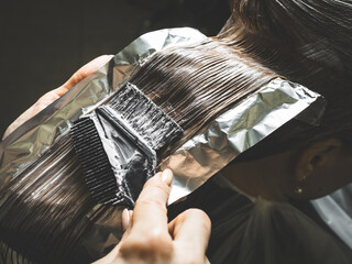 Hairdresser is applying bleaching powder on woman's hair