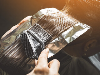 Hairdresser is applying bleaching powder on woman's hair - obrazy, fototapety, plakaty