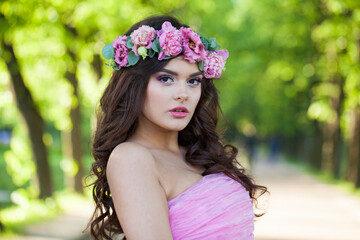 Lovely young adult lady with with long hair, make-up and pink flower in spring park. Beauty woman portrait