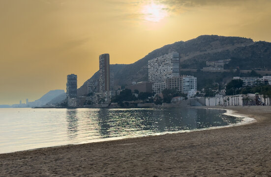 View of Albufereta beach and ocean front buildings on the Mediterranean coast of Alicante, Spain, on a hazy day due to Sahara desert dust in the air, known as calima.