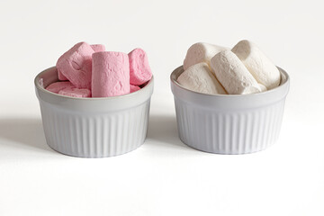 sweet fluffy white and pink marshmallows in bowls on white surface close up