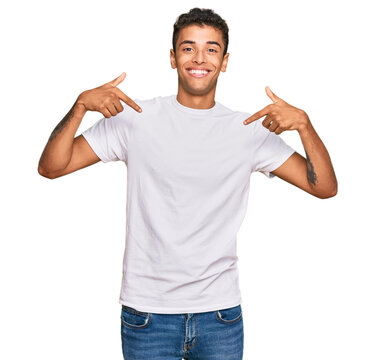 Young handsome african american man wearing casual white tshirt looking confident with smile on face, pointing oneself with fingers proud and happy.