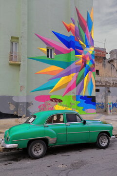 Old green almendron car -yank tank, Chevrolet classic- from 1952 on Campanario Street next to a street artwork by Okuda San Miguel. Havana-Cuba-114
