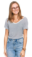 Obraz premium Beautiful young blonde woman wearing casual clothes and glasses looking away to side with smile on face, natural expression. laughing confident.