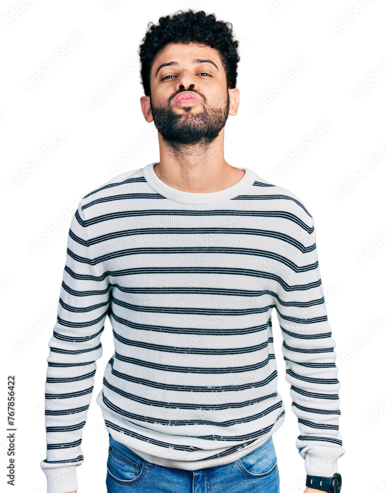 Poster young arab man with beard wearing casual striped sweater looking at the camera blowing a kiss on air