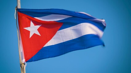 Cuban flag flying in the wind on a backdrop of blue sky. National symbol. Close-up view of the Cuba national flag waving in the wind.