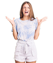 Young beautiful blonde woman wearing tye die tshirt celebrating mad and crazy for success with arms...