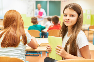 Girl holding book while sitting in class