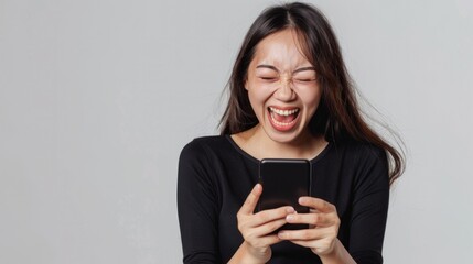 Fototapeta premium Asian woman delighted with good news on her smartphone, celebrating a positive surprise, isolated on a white background.