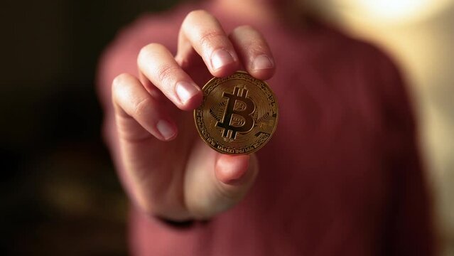 Woman hand showing a bitcoin golden coin to the camera. Bullish BTC, cryptocurrency, 2p2 exchange and blockchain concept