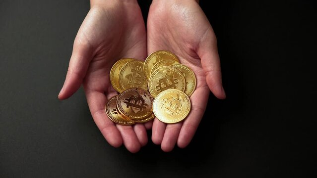 Hands showing a pile of bitcoins golden coins on a black background. Bullish BTC, cryptocurrency, 2p2 exchange and blockchain concept