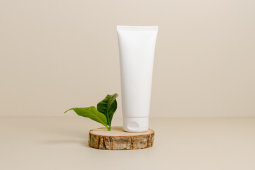 Mockup unbranded cream tube on wooden podium with green leaf, minimal aesthetic style. Skincare...