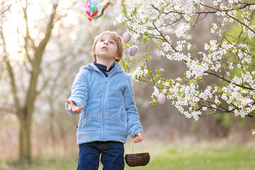 Beautiful blond child, boy, holding twig, braided whip made from pussy willow, traditional symbol of Czech Easter used for whipping girls and basket with eggs