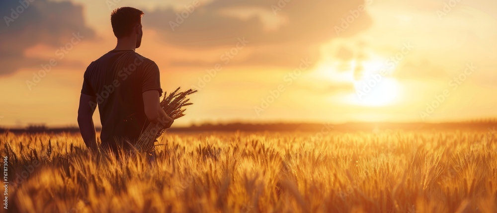 Poster agrinomist holding ears of wheat in the hands of a man in a golden wheat field.