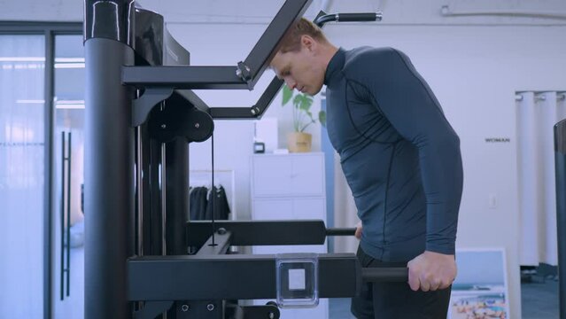 Young muscular man workout at gym doing dip exercise training chest and tricep muscles - side view slow motion