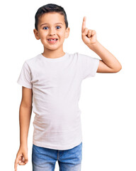 Little cute boy kid wearing casual white tshirt pointing finger up with successful idea. exited and happy. number one.