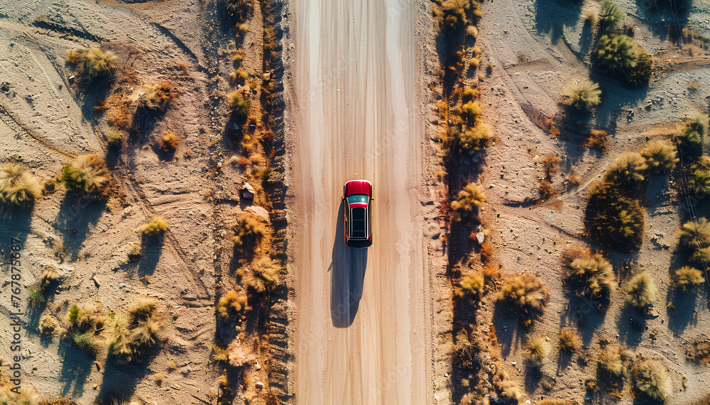 Wall mural car moves along an asphalt road in the desert top view