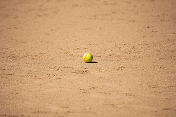 Softball with harsh shadow in the sand