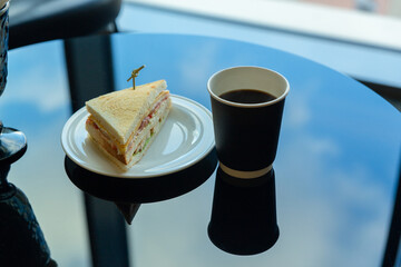 Paper cup of coffee and sandwich in the garden