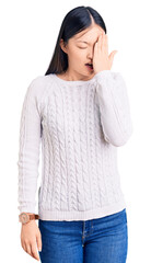 Fototapeta premium Young beautiful chinese woman wearing casual sweater yawning tired covering half face, eye and mouth with hand. face hurts in pain.