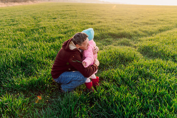 Naklejka na ściany i meble Grandfather and granddaughter hugging in the field with sunshine