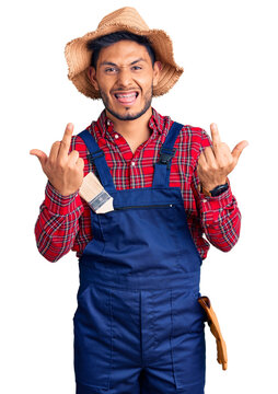 Handsome latin american young man weaing handyman uniform showing middle finger doing fuck you bad expression, provocation and rude attitude. screaming excited