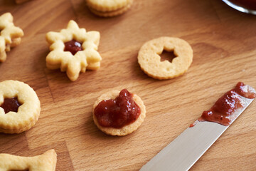 Filling traditonal Linzer Christmas cookies with strawberry marmalade, close up