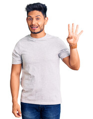 Naklejka premium Handsome latin american young man wearing casual tshirt showing and pointing up with fingers number four while smiling confident and happy.