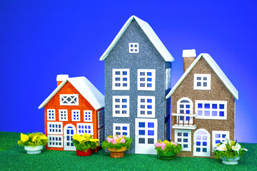 Three toy houses of different sizes with flowers next to them