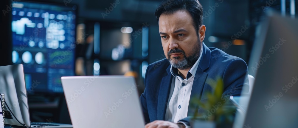 Aufkleber Typical office worker with laptop at his desk. Successful Latino IT software engineer working with laptop at desk. Diverse workplace with professionals. Front view.