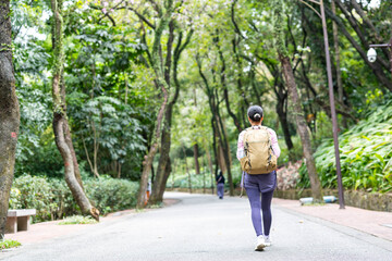 Back view of woman hiking with backpack outdoors