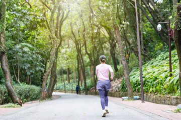 Fototapeta na wymiar Back view of woman exercising and jogging in park