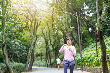 Woman taking a break and drinking water while running in the park