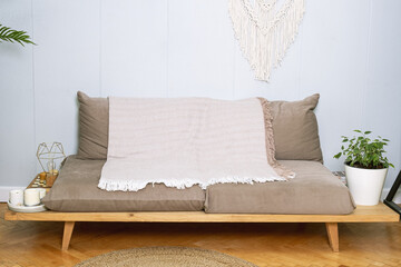 A low sofa without armrests with a blanket thrown over it - obrazy, fototapety, plakaty