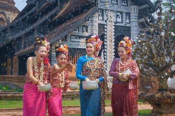 Fototapeta na wymiar Songkran festival . Pretty Asian women playing with water-splashing Songkran. Beautiful Thai traditional dress costumes according to Thai culture to celebrate of the people Thailand New Year.